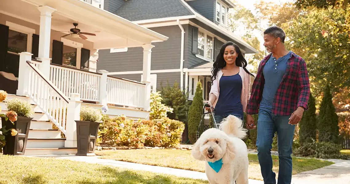 colorado homeowners association management - couple walking dog past beautiful home